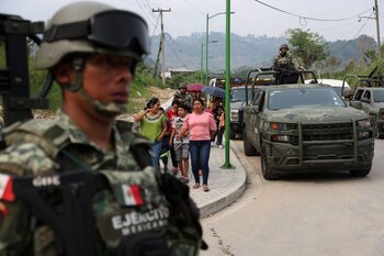 Soldados vigilan mientras personas que