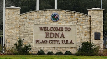 Letrero de piedra de la ciudad de Edna en Texas con el texto Welcome to Edna Flag City, U.S.A. y el sello oficial de la localidad