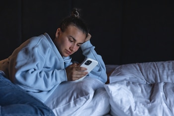 Una mujer consulta su móvil en la cama antes de dormir. (Magnific)