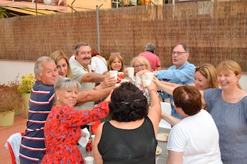 Diez personas adultas, hombres y mujeres, brindan con vasos blancos descartables alrededor de una mesa al aire libre, con una valla de caña de fondo