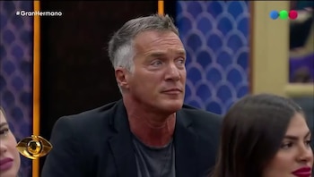 Primer plano de Eduardo, un hombre de mediana edad con cabello gris y una chaqueta oscura, mirando hacia la derecha en el set de Gran Hermano
