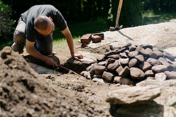 Victor Guadalup, who has been making pachamancas since age 15, checks on the dish inside the underground pit at Esmeralda, in Andover, Vt., on June 16, 2021. Thousands of miles from its place of origin, pachamanca — a centuries-old form of underground cooking — gets a spotlight. (Kelly Burgess/The New York Times)