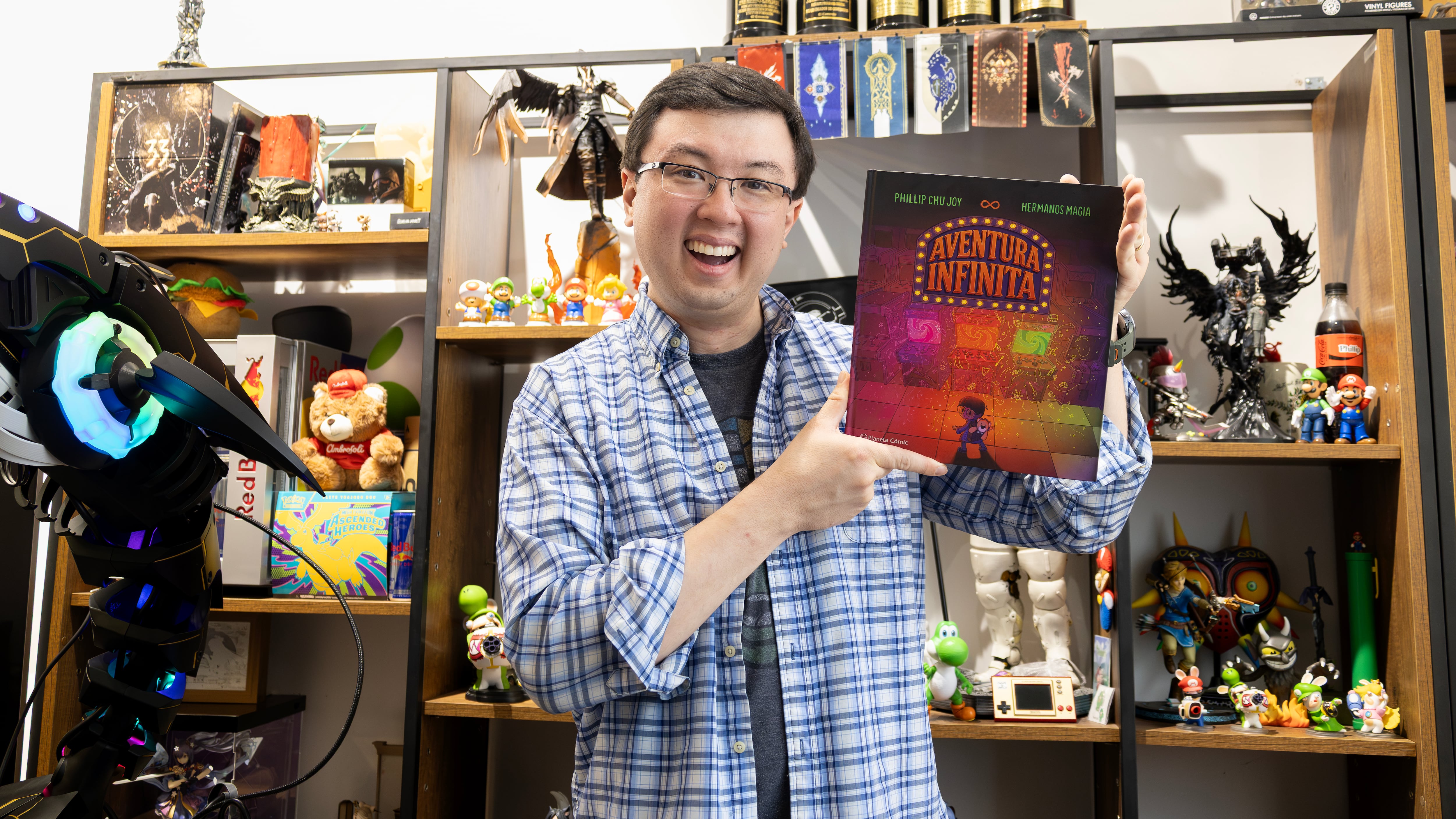 Phillip Chu Joy sonríe mientras muestra su primer libro-juego ‘Aventura Infinita’ en un espacio rodeado de elementos de colección. (Carlos Diaz)