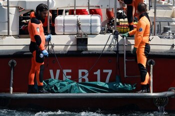 Dos submarinistas sacan un cuerpo del naufragio de un yate de lujo frente a las costas de Porticello, cerca de la ciudad siciliana de Palermo, Italia, a 23 agosto de 2024. (REUTERS/Louiza Vradi)