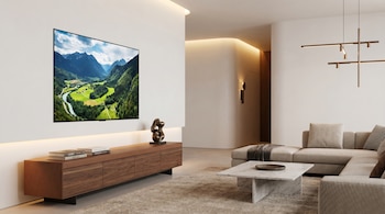 Salón moderno con un televisor OLED empotrado en la pared blanca, un mueble bajo de madera, un sofá seccional beige y una mesa de mármol.