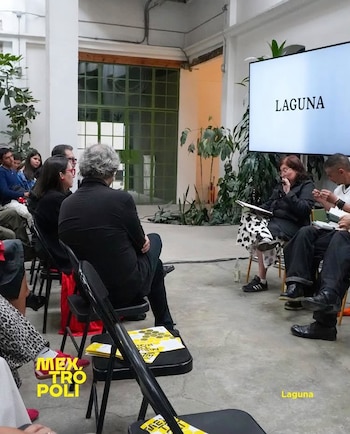 Personas sentadas en sillas plegables negras escuchan a una ponente junto a una pantalla con la palabra Laguna