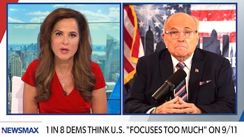 Pantalla dividida del canal Newsmax con una presentadora a la izquierda y Rudy Giuliani a la derecha frente a una bandera de Estados Unidos
