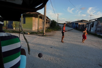 El conductor de bicitaxi Renier Gonzales, de 37 años, pasa junto a niños que juegan béisbol en la calle en Isabela de Sagua, Cuba (REUTERS/Alexandre Meneghini/Archivo)