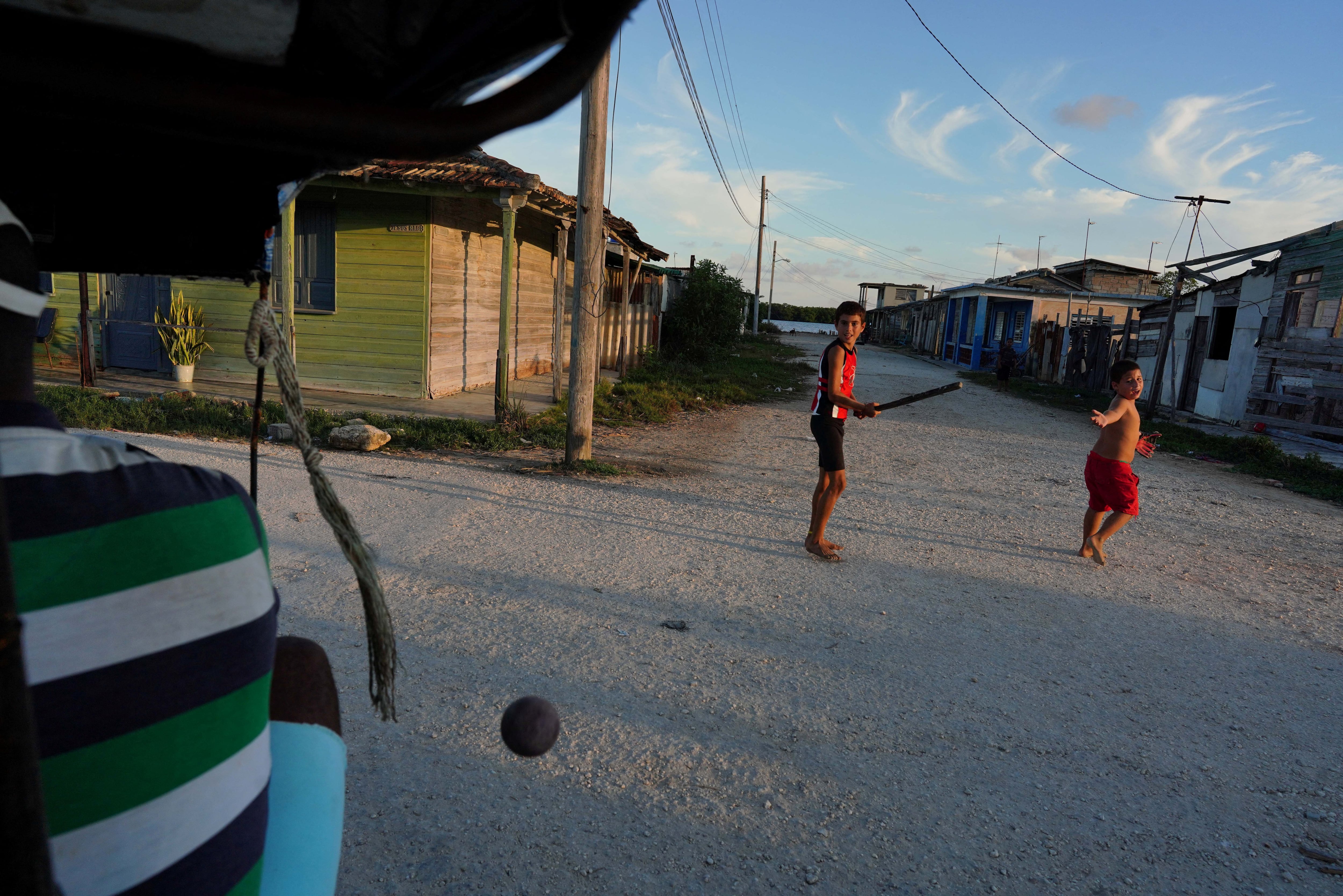 El conductor de bicitaxi Renier Gonzales, de 37 años, pasa junto a niños que juegan béisbol en la calle en Isabela de Sagua, Cuba (REUTERS/Alexandre Meneghini/Archivo)