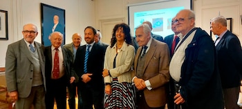 Un grupo de personas posa de pie en una sala frente a una pantalla de proyección que muestra una presentación digital