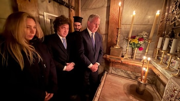 Javier Milei y su hermana, Karina, junto a otros hombres, dentro de una iglesia con velas encendidas y objetos religiosos en un entorno de piedra