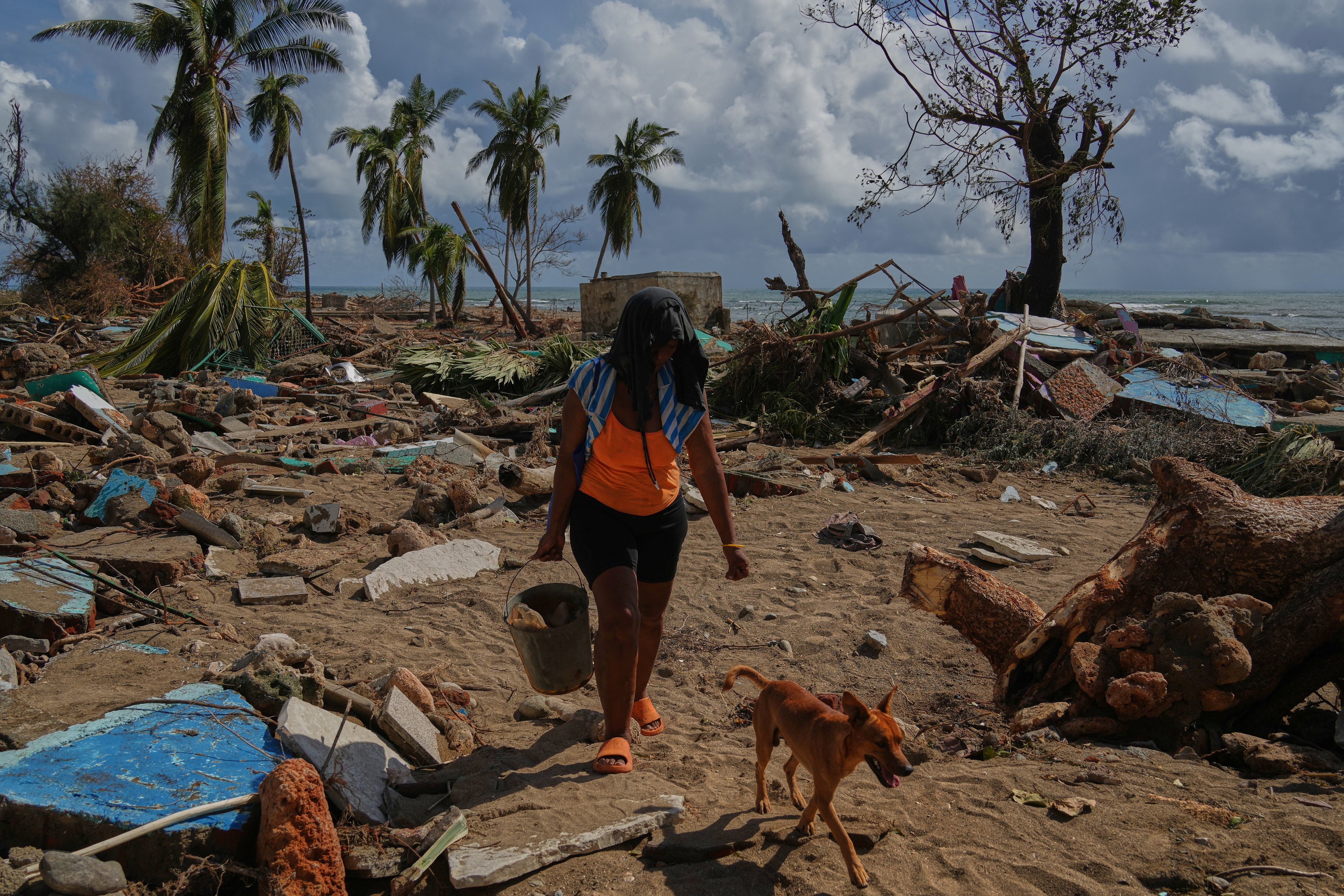 Una mujer y su perro caminan entre las ruinas de las casas destruidas por el huracán Melissa en Boca de dos Ríos, Cuba, el jueves 30 de octubre de 2025 (Foto AP/Ramón Espinosa)