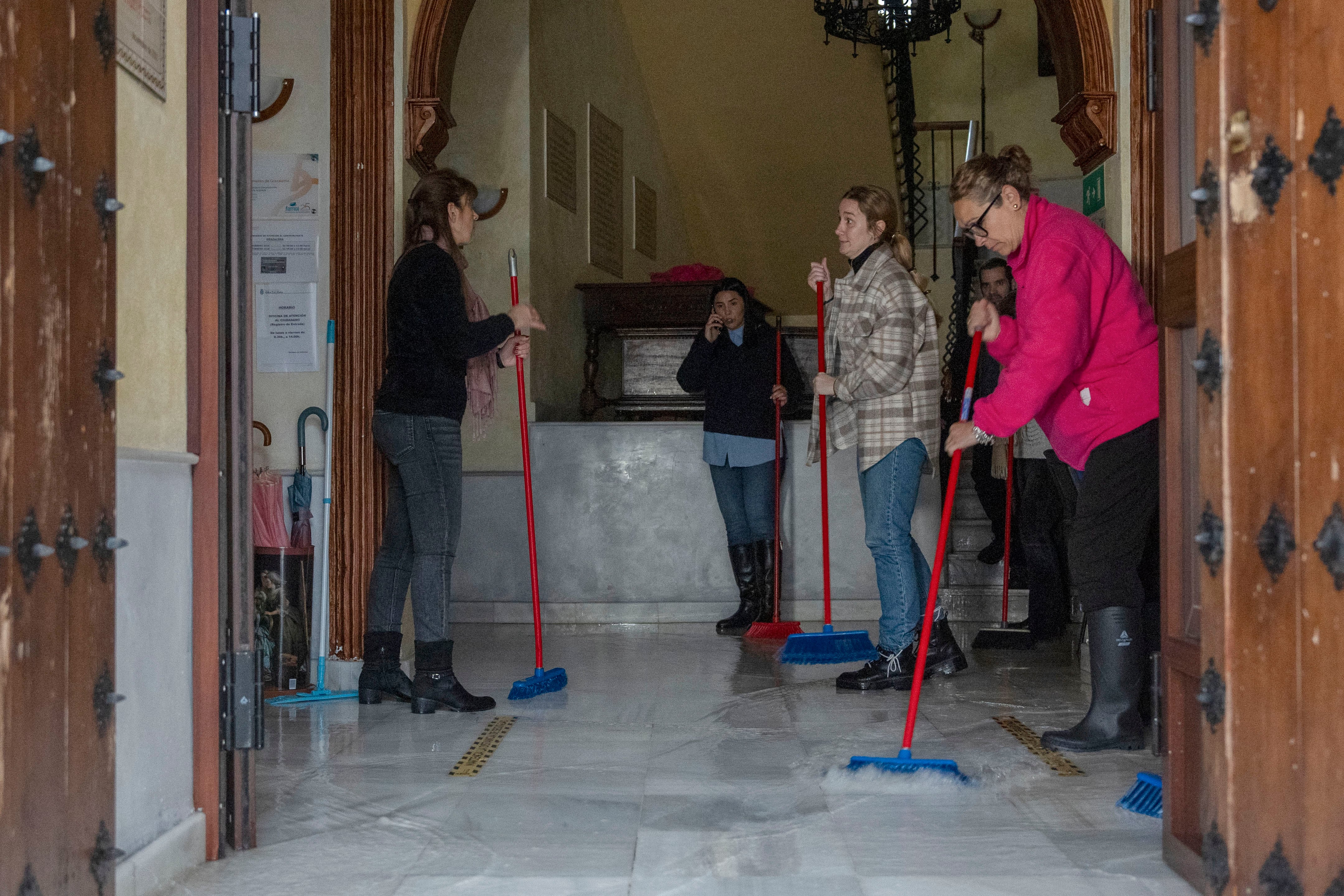 Vecinos de Grazalema intentan achicar agua de sus casa y locales debido a las intensas lluvias que se registran este miércoles en la localidad gaditana. (EFE/Román Ríos)