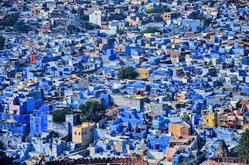 Vista aérea de un conjunto denso de casas con fachadas y azoteas de color azul y beige en una zona urbana