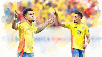Dos futbolistas con camiseta amarilla, pantaloneta azul y detalles rojos. Uno con el número 7, el otro con el 21. Hacen gestos con las manos.