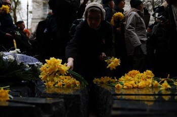 Una mujer coloca flores amarillas en el Monumento a Szmul Zygielbojm durante el 80mo aniversario del levantamiento del ghetto de Varsovia, el miércoles 19 de abril de 2023, en Varsovia, Polonia. (AP Foto/Michal Dyjuk)