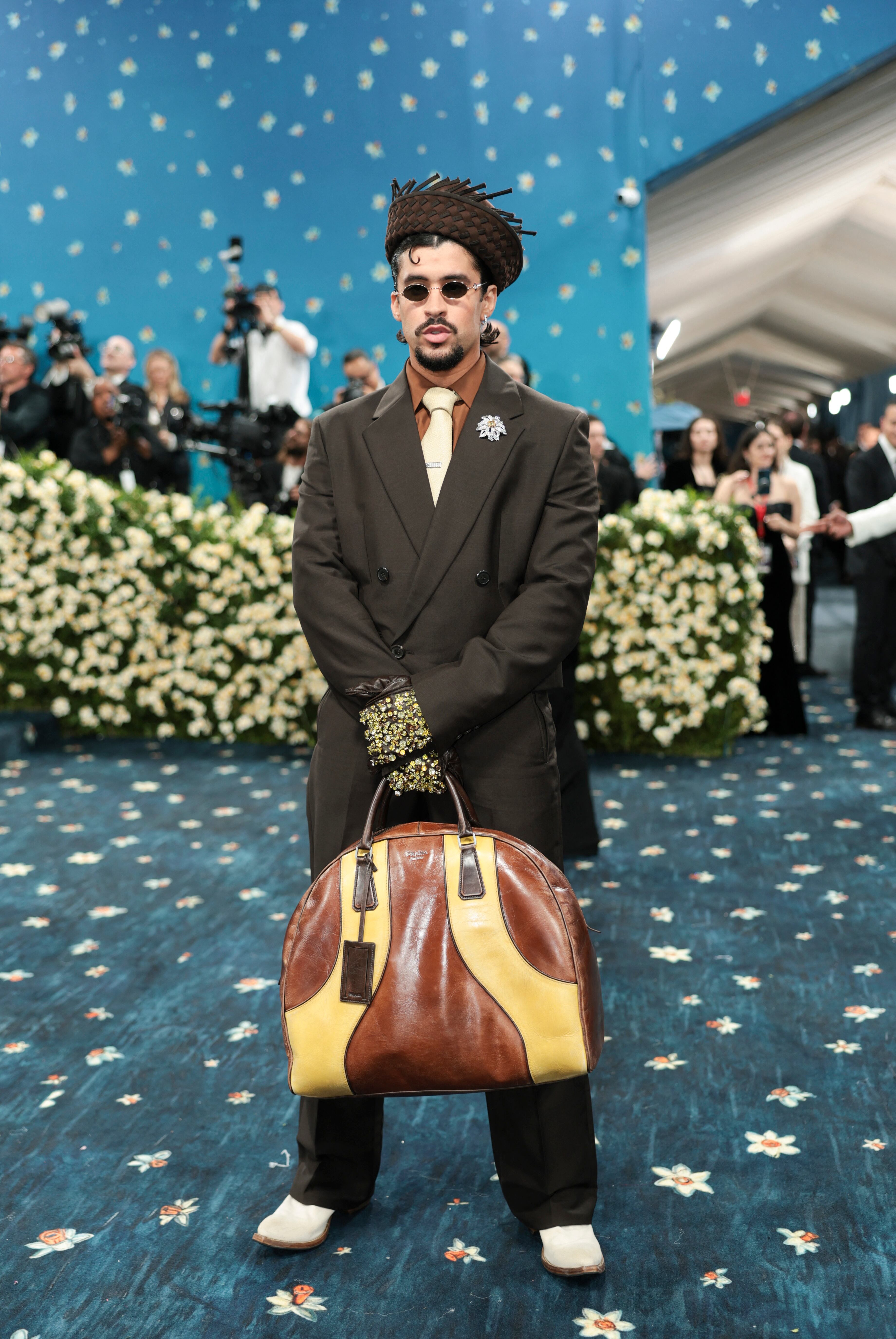El traje marrón oscuro con guantes brillantes y bolso grande destaca la preferencia de Bad Bunny por los accesorios audaces y la combinación de texturas (REUTERS/Mario Anzuoni)