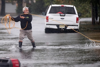 Jose Rosario saca un cable de extensión de su garaje inundado para conectarlo a un generador en la calle Catherine, el sábado 26 de septiembre de 2026, en Long Branch, Nueva Jersey (AP /Noah K. Murray)