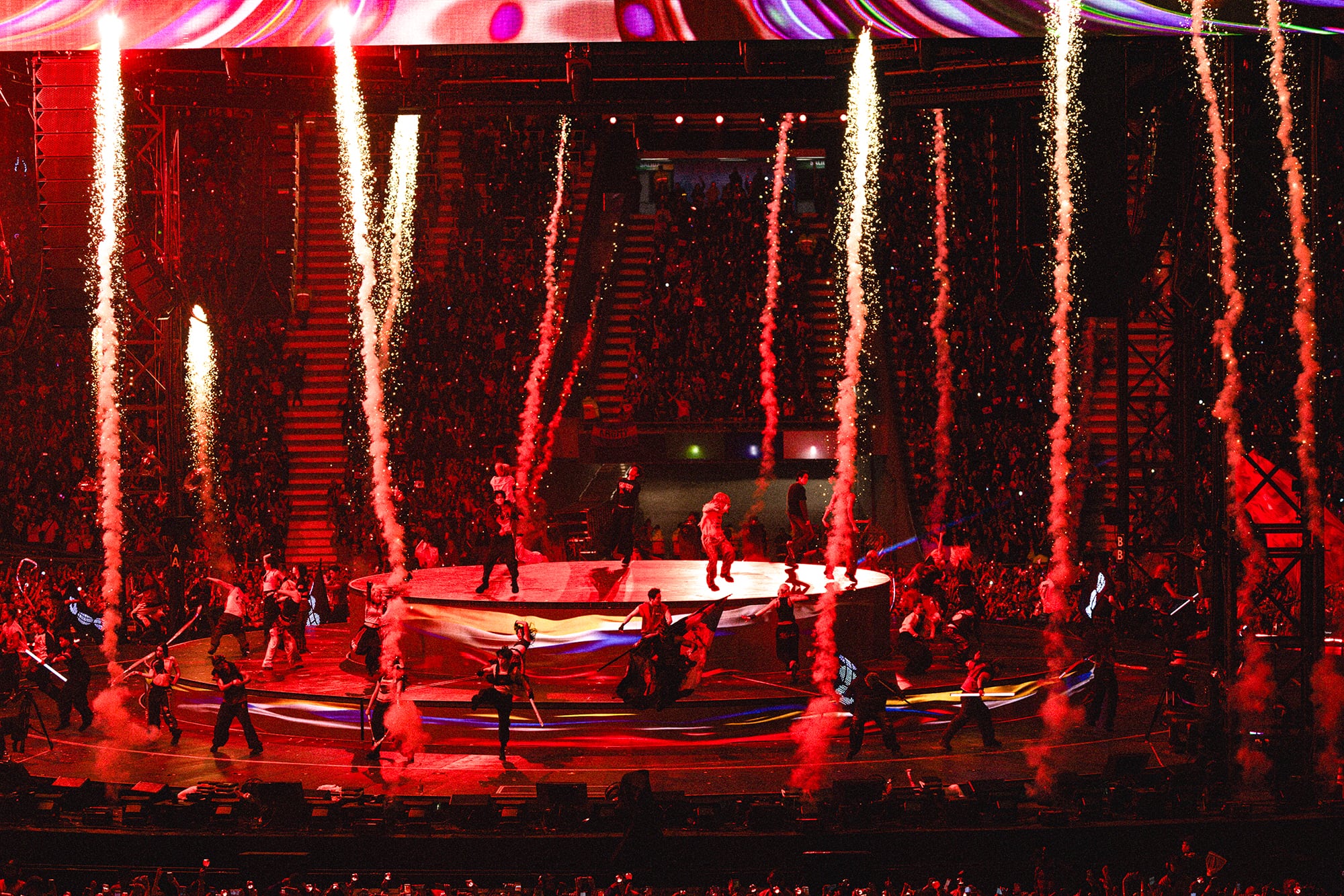 Los integrantes del grupo musical BTS realizan su presentación en un escenario iluminado de rojo con efectos de pirotecnia ante el público en Argentina. (Crédito: HYBE/BIGHIT MUSIC )