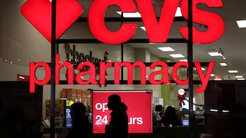 FILE PHOTO: People walk by a CVS pharmacy store in Manhattan, New York City
