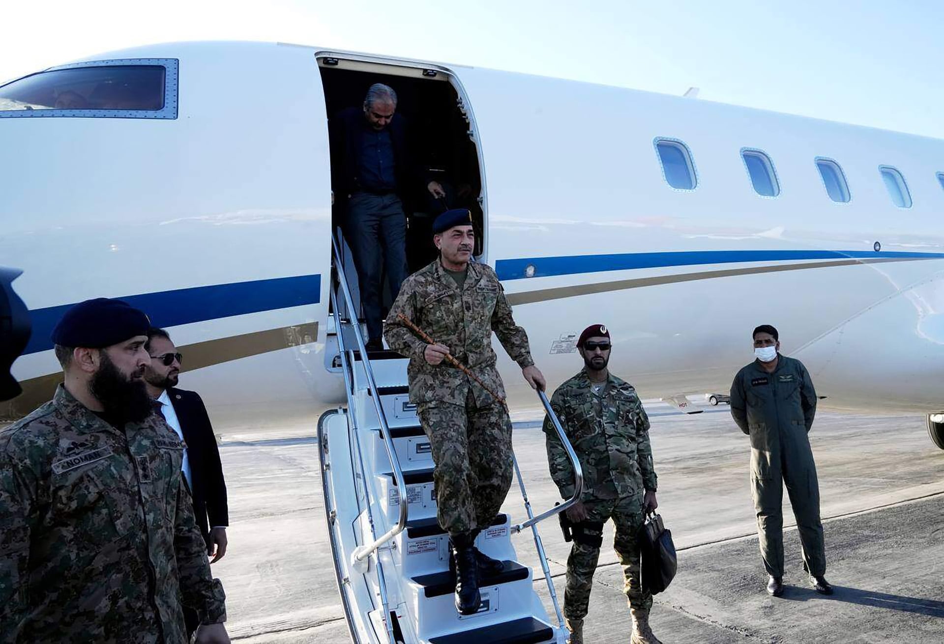 El Jefe del Estado Mayor del Ejército de Pakistán, Asim Munir, desciende las escaleras de un avión, rodeado de personal militar. (APNews)