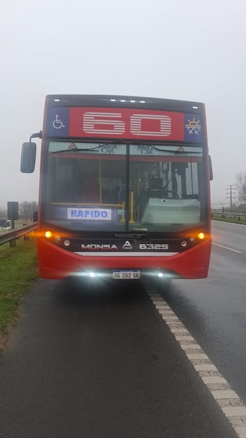 Autobús rojo con el número 60, cartel "Rápido", logos Monsa, Todobus y Agrale, luces encendidas y matrícula argentina AG 202 SR en una carretera
