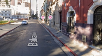 Vista de la calle Balcarce en Córdoba, con edificios a ambos lados, autos estacionados y un bordillo rojo en la acera