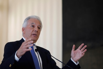 Primer plano de Lawrence Bernstein, un hombre de cabello gris con traje azul marino y corbata azul, hablando en un micrófono y gesticulando con ambas manos. El fondo es claro y oscuro