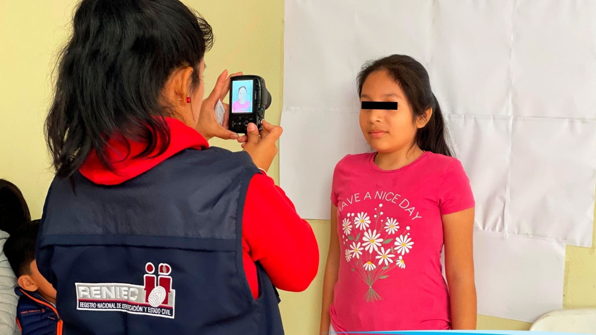 Una funcionaria del Reniec ayuda a tramitar el DNI electrónico completamente gratis a una menor en una de las campañas itinerantes. (Composición: Infobae Perú)
