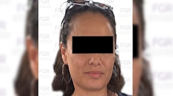 Retrato de una mujer con los ojos cubiertos por una barra negra, gafas sobre la cabeza y fondo con logotipos institucionales.
