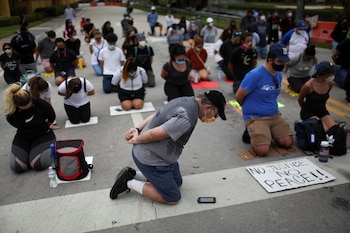 Manifestantes se arrodillan al participar en una protesta contra la muerte de George Floyd bajo custodia policial, frente al complejo de golf Trump National Doral en Florida el 6 de junio de 2020. REUTERS/Marco Bello