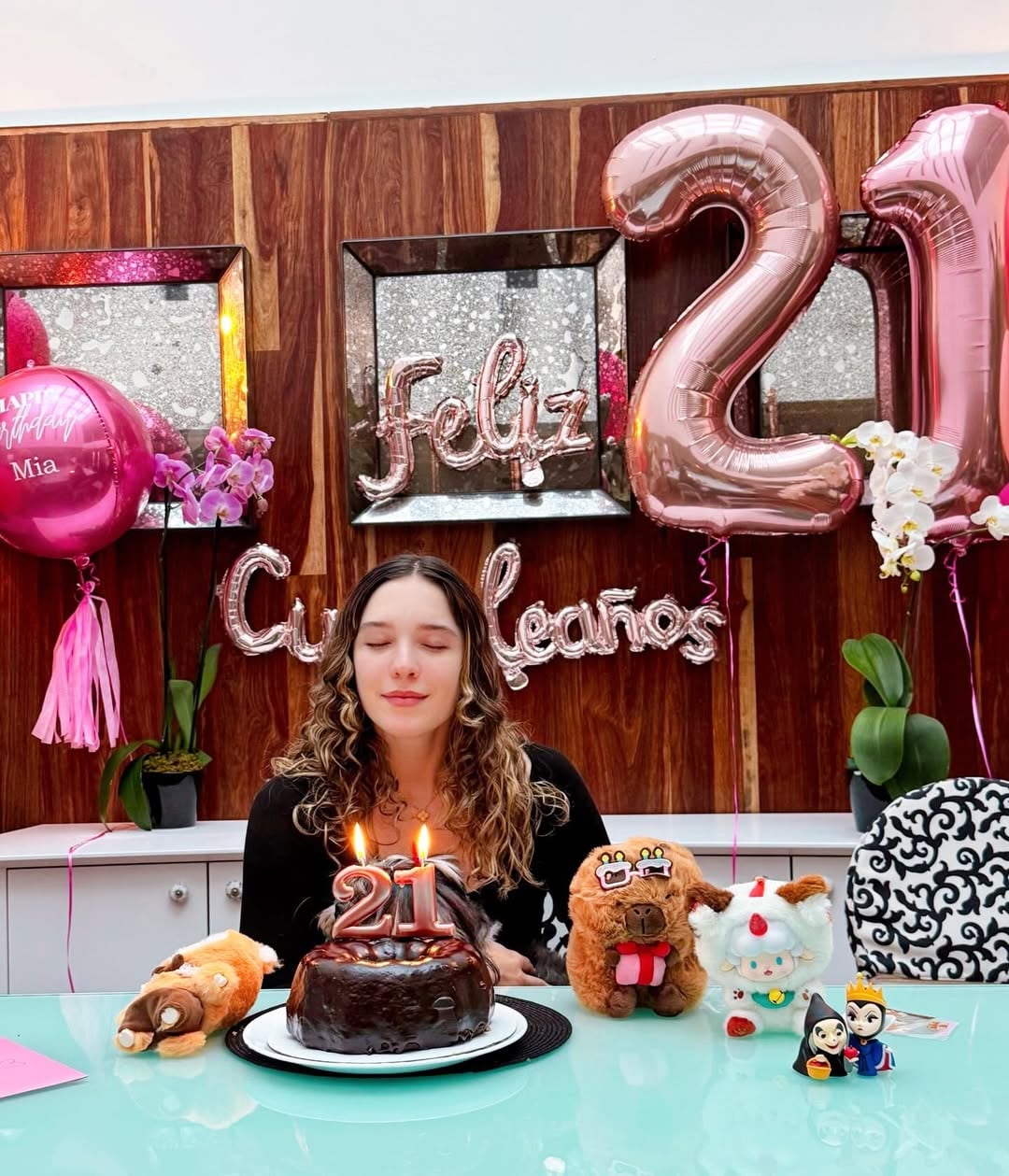 Mía Rubín sopla las velas de su pastel de cumpleaños número 21, rodeada de decoraciones festivas. (Instagram)