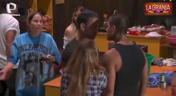 Diego Chávarri y Paul Michael se enfrentan cara a cara en un interior, rodeados de otros concursantes. Una mujer en camiseta azul observa la escena