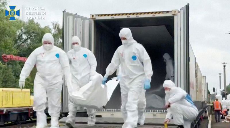 Personas con trajes transportan lo que se dice que son restos de soldados ucranianos recibidos de Rusia en un lugar desconocido (Servicio de Seguridad de Ucrania/Handout via REUTERS)
