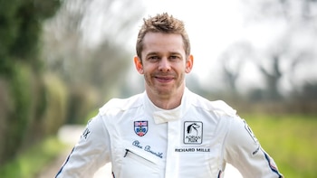 El piloto Alex Brundle sonríe mirando al frente con un traje de carreras blanco que lleva su nombre bordado en el pecho