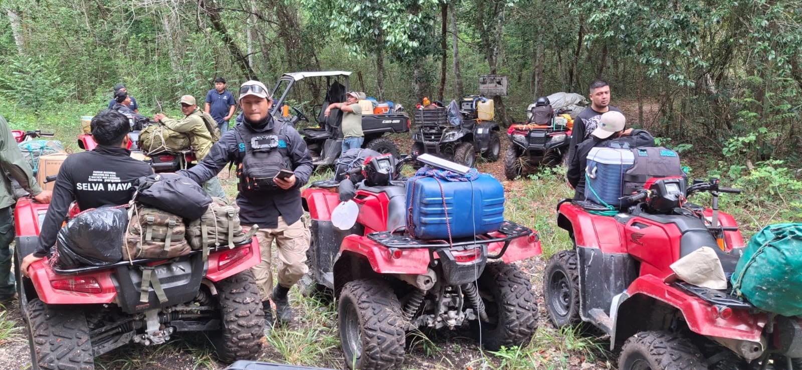 Un grupo de guardaparques prepara sus cuatrimotos y vehículos todoterreno cargados con equipaje durante una expedición por la Selva Maya. (Francisco Asturias )