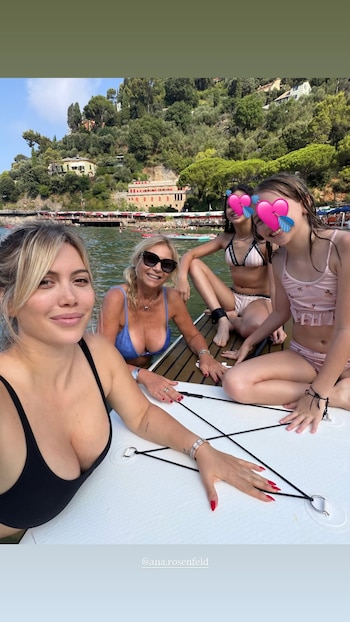 Wanda Nara y tres mujeres posan en traje de baño sobre una tabla blanca flotando en el agua; detrás se ve una montaña verde con construcciones