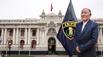 Un hombre con traje permanece junto a una bandera del Instituto Nacional Penitenciario y el edificio del Congreso del Perú al fondo.