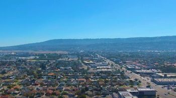 Vista aérea de Torrance, California, mostrando barrios residenciales, calles con tráfico, edificios comerciales y montañas distantes bajo cielo azul
