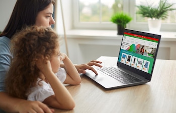 Una mujer y una niña frente a una computadora portátil que exhibe la página web de Provincia Compras sobre una mesa de madera