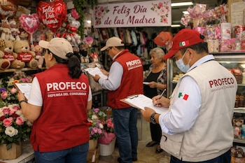 Tres inspectores de PROFECO revisan documentos en un negocio con flores, globos y osos de peluche, decorado para el Día de las Madres.
