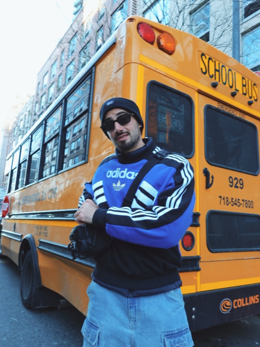 El animador, de gorro de lana y lentes de sol, con uno de los tradicionales buses escolares de Estados Unidos