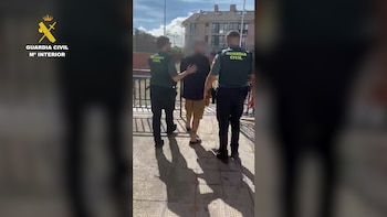 Dos agentes de la Guardia Civil trasladan a un hombre con el rostro pixelado por una calle en una zona residencial