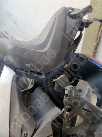 Primer plano de componentes internos y externos de una motocicleta con superficies de plástico y metal cubiertas de polvo. Se observan cables y tornillos