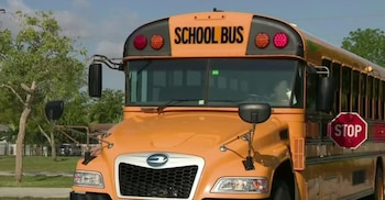 Un autobús escolar amarillo con el letrero 'SCHOOL BUS' en la parte superior y una señal de 'STOP' roja extendida en su lateral