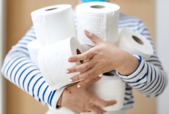 Una mujer sosteniendo varios rollos de papel higiénico (Freepik)