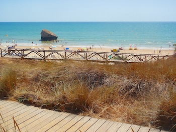 Una playa con arena y el agua muy claro. Una torre dada la vuelta.