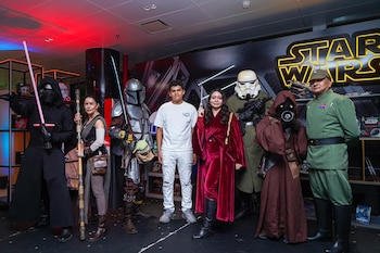 Roglok, Snarky Jay y cinco cosplayers de Star Wars, incluyendo personajes emblemáticos, posan frente a un letrero luminoso