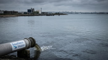 Vista panorámica del estrecho de Solent con cielo nublado y una tubería industrial de Southern Water vertiendo líquido, junto a plantas de tratamiento al fondo.
