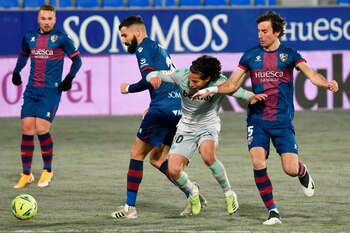 Los jugadores de la SD Huesca Dimitrios Siovas (i) y Pedro Mosquera (d) presionan al centrocampista mexicano del Real Betis, Diego Lainez durante el partido de la jornada 18 de Liga en Primera División jugado en El Alcoraz, en Huesca. EFE/JAVIER BLASCO
